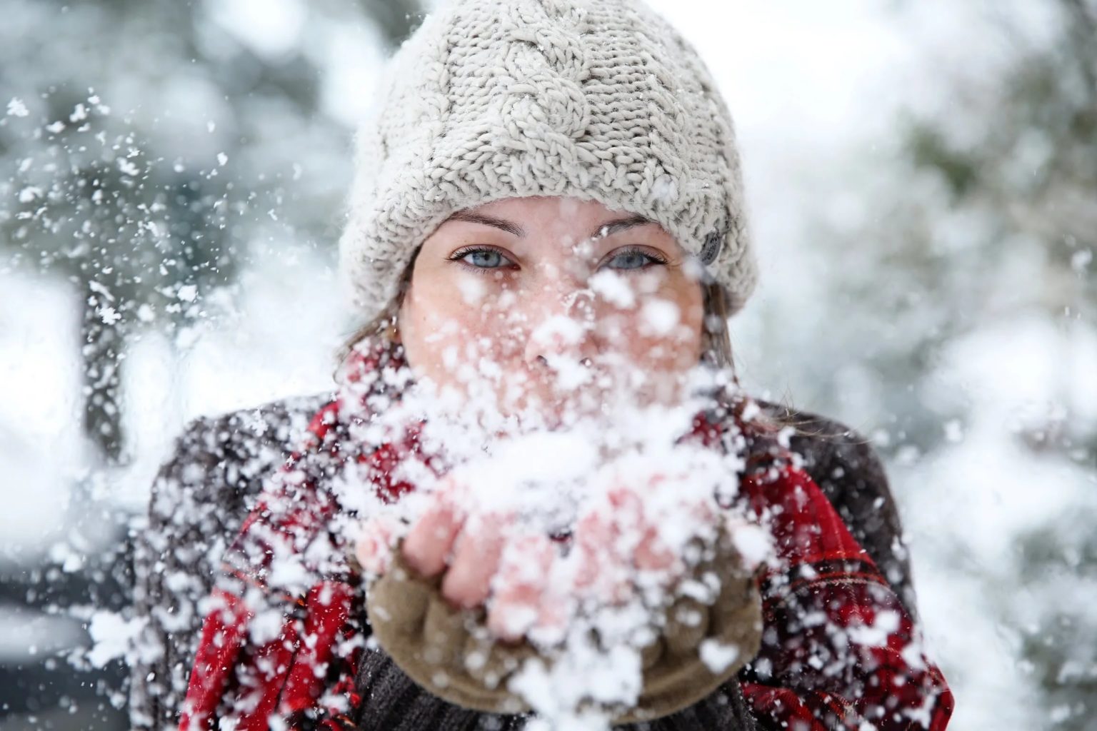 Девушка сдувает снег с ладоней